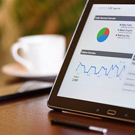 Tablette affichant des graphiques de statistiques de trafic, posée sur un bureau à côté d'une tasse